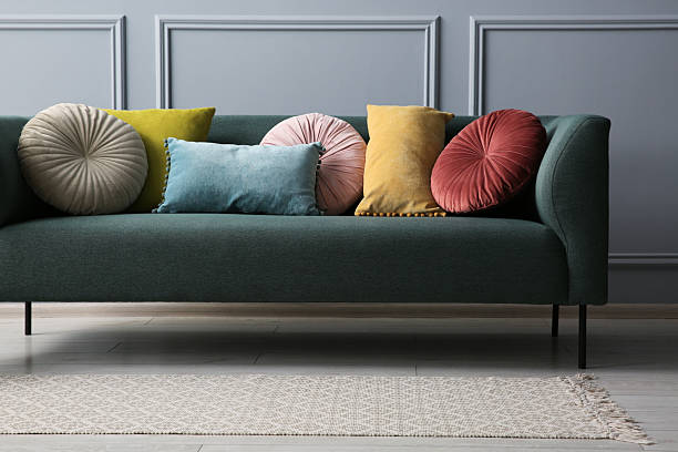 istock Stylish sofa with different cushions near grey wall 2214772489