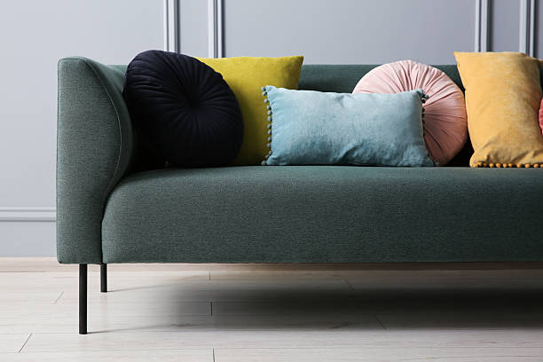 istock Stylish sofa with different cushions near grey wall 2214772500