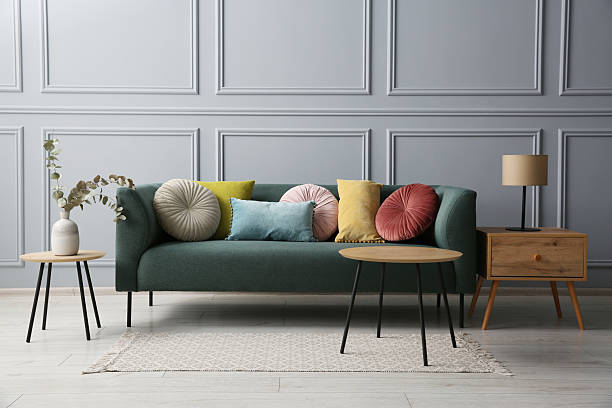 istock Stylish sofa with cushions, lamp and eucalyptus branches on side tables in room 2214772512