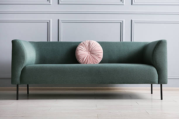 istock Stylish sofa with cushion near grey wall 2214772547
