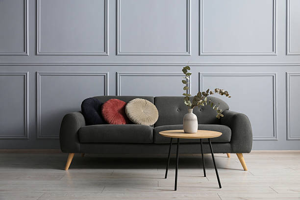 istock Stylish sofa with cushions and eucalyptus branches in vase on coffee table in room 2214772558