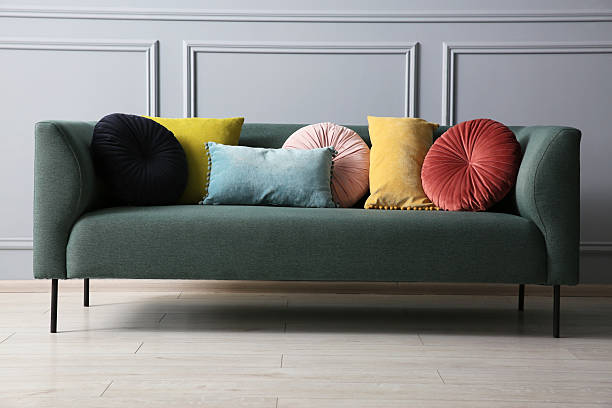 istock Stylish sofa with cushions near grey wall 2214772673