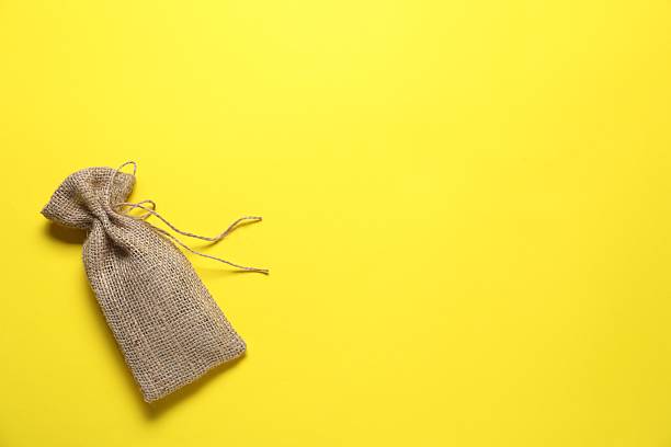 istock One burlap sack on yellow background, top view. Space for text 2214773503