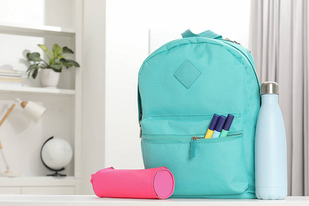 istock Backpack with different school stationery and bottle on desk in room 2214773869