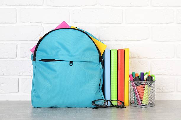 istock Backpack with different school stationery on light grey table near brick wall 2214773905