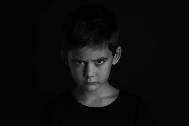 istock Angry little boy on dark background. Black and white effect 2214773964