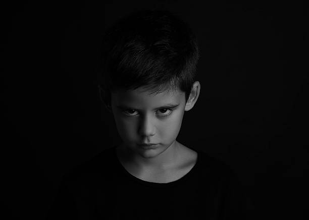 istock Angry little boy on dark background. Black and white effect 2214774072