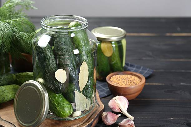 istock Making pickles. Fresh cucumbers and spices in jars on black wooden table 2214774660