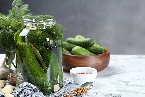 istock Making pickles. Fresh cucumbers and spices in jar on white marble table 2214774664