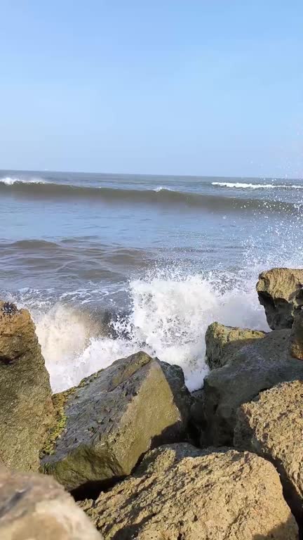 The ocean is calm and the rocks are grey. Puerto Mocho, Bocas de ceniza, Barranquilla, Colombia