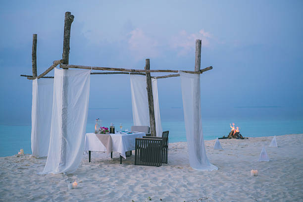 istock Dining table on edge of sea at sunset, beach fire 2214776790