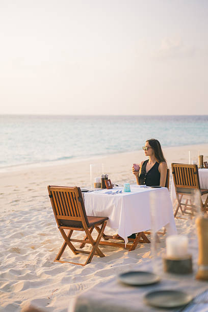istock Young woman relaxes at beach cafe at sunset 2214776793