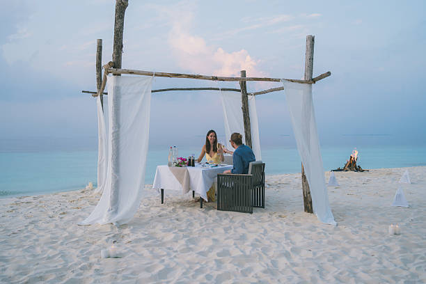 istock Young couple enjoy dinner on beach at sunset 2214776802