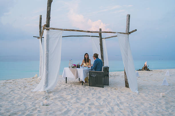 istock Young couple enjoy dinner on beach at sunset 2214776805
