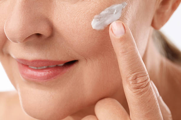 istock Senior woman applying face cream on white background, closeup 2214778001