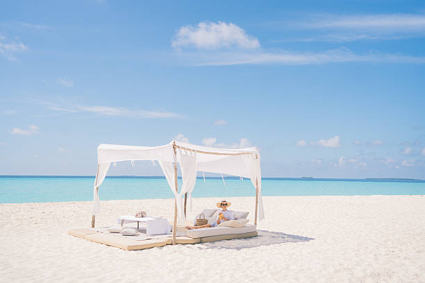 Tropical paradise scene with umbrella and jetty in Indian sea at Dhiffushi Holiday island at South Ari atoll, Maldives. Beautiful turquoise Indian ocean sea with white sand. Luxury travel holidays background. Property released. Photo taken by Sony a7R II, 42 Mpix.