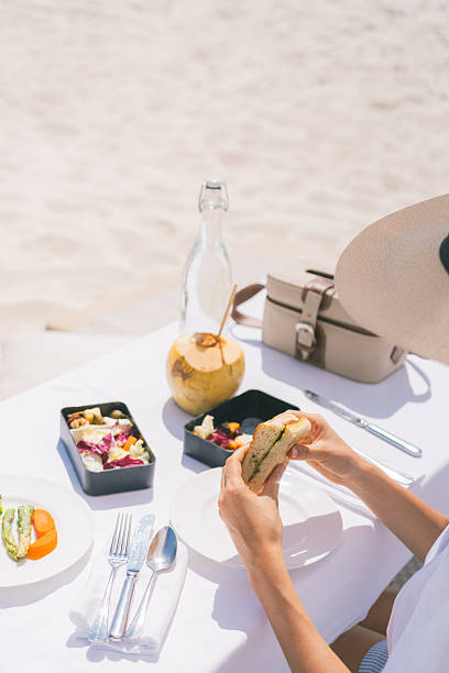 Young woman enjoys picnic lunch under beach umbrella