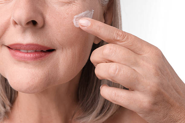 istock Senior woman applying face cream on white background, closeup 2214778920