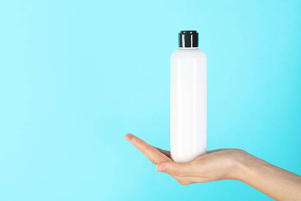 istock Woman with shampoo bottle on light blue background, closeup. Space for text 2214780552