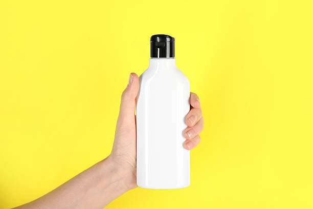 istock Woman with shampoo bottle on yellow background, closeup 2214780568
