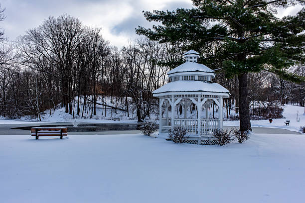 Sunny winter snowfall theme. Bench with small garden house under frozen tree