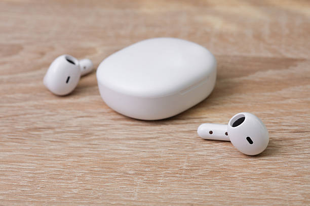 istock White Wireless earphones with charging case on table 2214787396