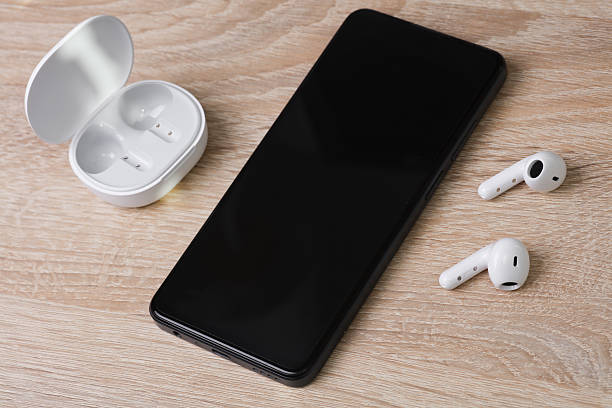 istock White Wireless earphones with charging case and smartphone on table 2214787413