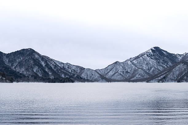 Chuzenji Lake with ripple on water surface and snow mountain background