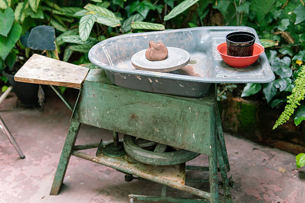 Traditional pottery wheel placed in a garden, showing the tools and materials ready for crafting ceramics