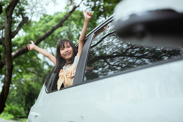 istock Child enjoys a joyful ride with arms raised through car window in a green park setting on a sunny day 2214794939