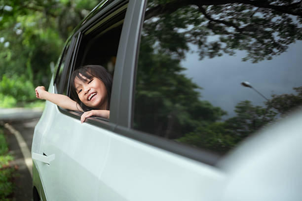 istock Happy child enjoying a car ride with the window down on a sunny day surrounded by greenery 2214794941