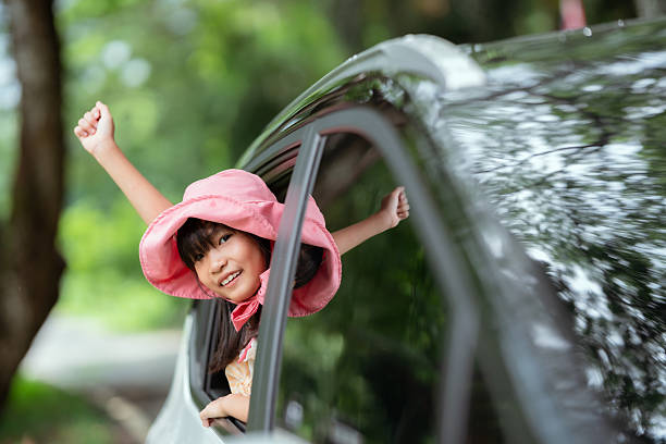 istock Happy child enjoying a car ride with the window down on a sunny day surrounded by greenery 2214794955