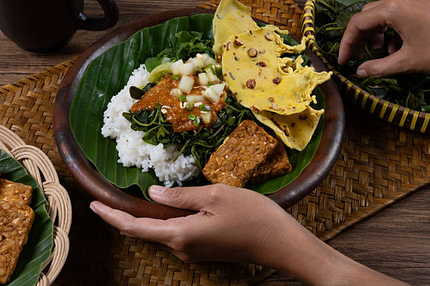 istock Hands Preparing Traditional Indonesian Pecel in Clay Plate 2214795142