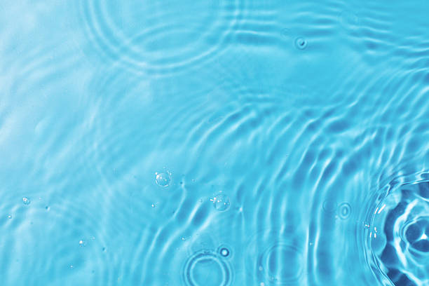 Rippling water texture background for design and decoration. Pouring and splashing clear water on light blue background upper close view