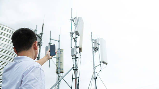 istock Teenage boy using mobile phone near 5G communications tower 2214801338
