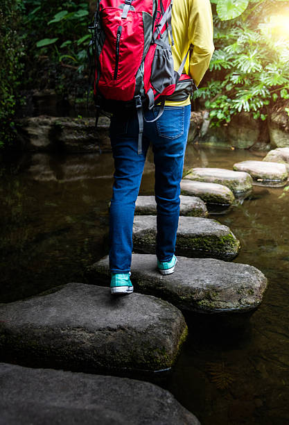 istock Female backpacker walking on stepping stones 2214801490
