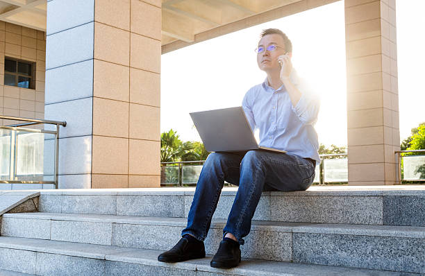 istock Businessman sitting on stairs and using laptop 2214801683