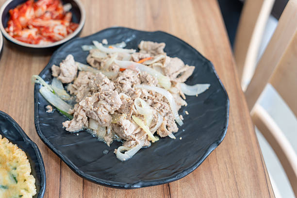 istock Traditional Korean side dish, Tir-fried pork belly with onions and side dish on table 2214804530