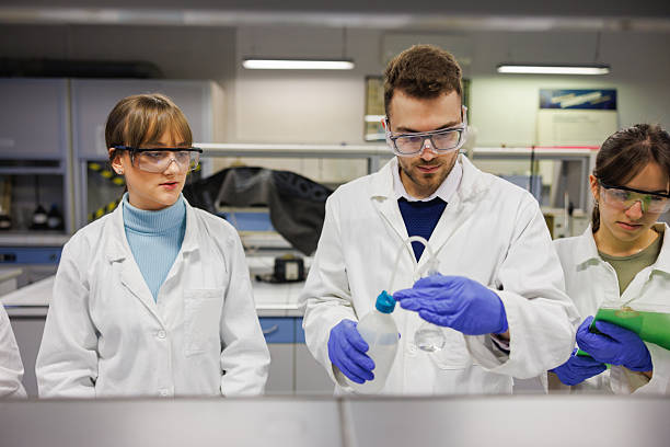 istock Assistant lecturer with students in faculty lab, wearing lab coats and surgical gloves in practice class 2214805804
