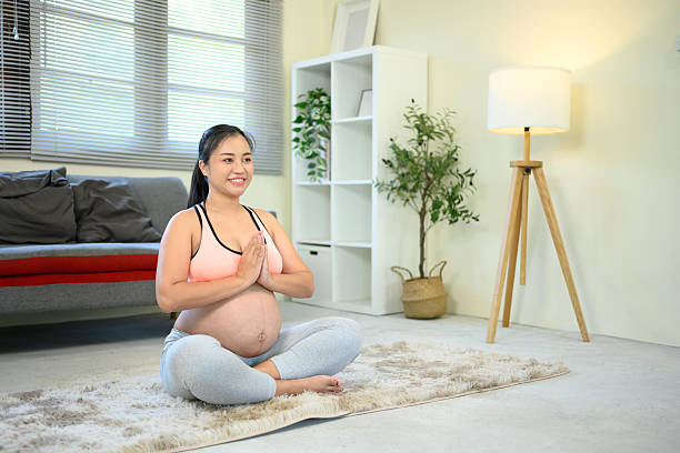 istock Expectant mother doing a meditation pose on soft carpet. Prenatal wellness concept 2214806553