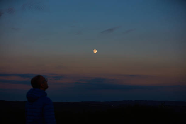 istock Silhouette of a man observing Moon, Milky Way stars, planets and other celestial objects from a dark countryside location. 2214810361