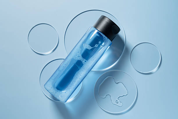 Natural cosmetic laboratory concept. Petri dish with blue toner or micellar water bottle on blue background top view, mockup