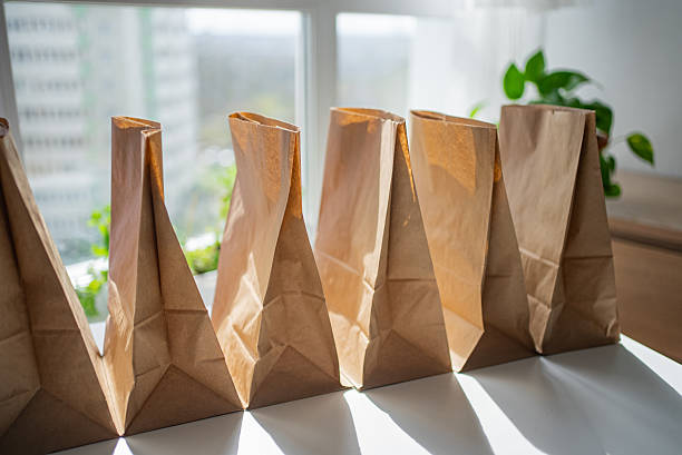 istock Brown paper shopping bags lying open on white surface, natural light streaming across empty containers waiting for grocery delivery 2214814548