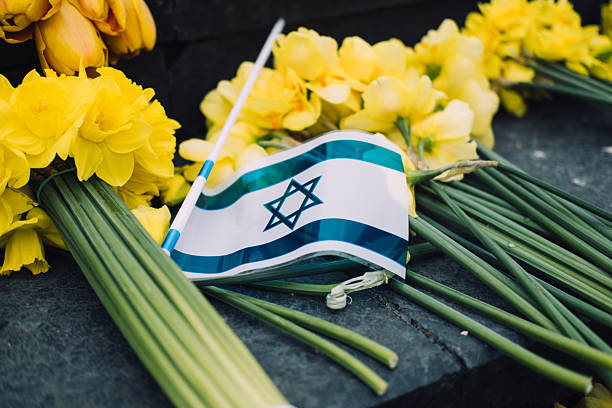 istock Israeli flag and yellow daffodils on stone steps, symbolizing Holocaust remembrance and national mourning 2214814833