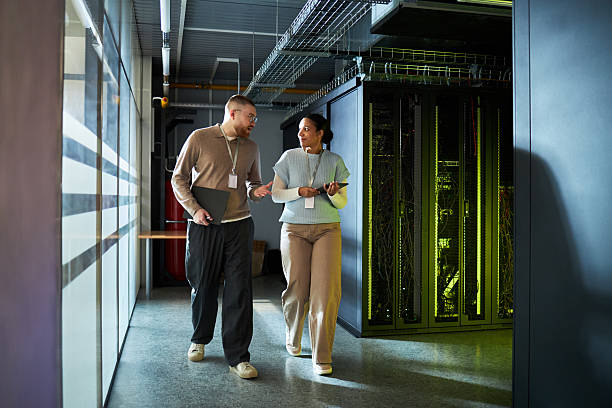 Colleagues Discussing Work while Walking in Server Room stock photo