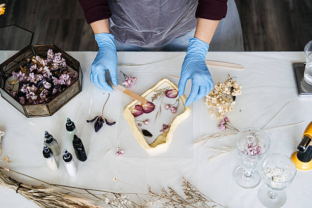 istock Hands arranging pressed flowers into resin frame, showcasing traditional crafts in modern DIY home decor. Eco-friendly, sustainable crafting techniques. 2214818057