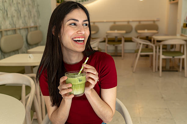 istock Young woman laughing and drinking matcha latte in cafe 2214821071