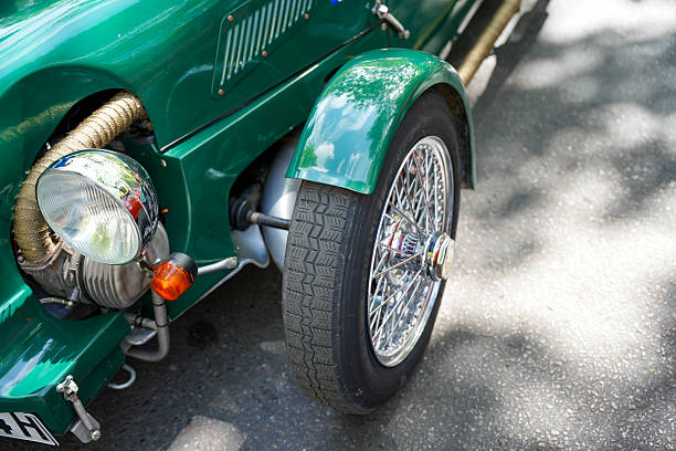 Germany Berlin May 11, 2025. Tires and Headlights Detailed View. Detailed view of a vintage car with classic tire tread, chrome-plated spoked wheels, and round headlights. The hand-wrapped insulation on the exhaust pipe gives the vehicle an authentic workshop look.