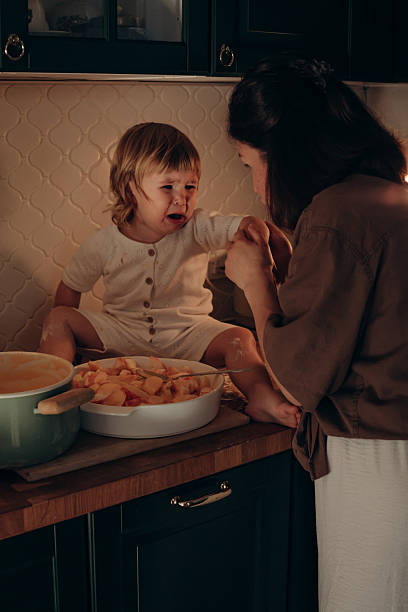 istock In a warm kitchen, a mother and her young child enjoy quality time while preparing fresh fruit. The little one sits on the counter, laughing as they help with the task 2214821394