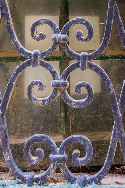 istock Rustic Iron Grille With Intricate Swirls Against a Dusty Glass Window 2214821856